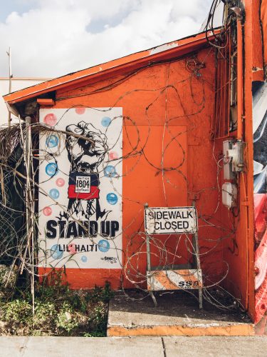 In Little Haiti (Miami, Florida, USA), one of Serge Toussaint's murals can be seen behind a wall of barbed wire.
