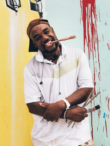 Little Haiti artist Serge Toussaint in front of one of his murals.