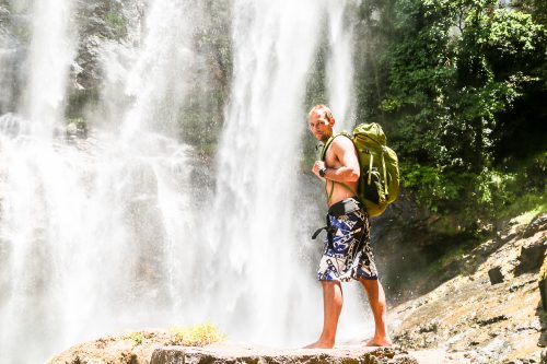 Matt Prior, Head of Adventure Academy, stands in front of a spectacular waterfall.
