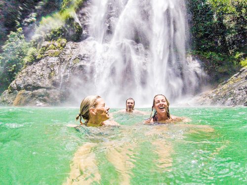 Three participants on an Adventure Academy trip swim in a turquoise natural pool.
