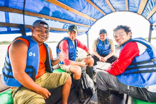 Tourists and locals aboard a small boat headed upstream in the Amazon region