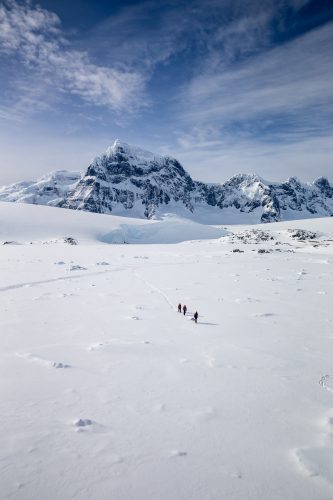 Tourists can be seen walking across the snow at Port Lockroy harbor.