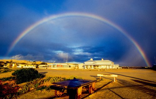 Hitchhiking Australia: a rainbow forms a perfect arc over a town in the outback.