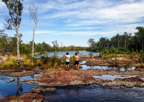 Travelers stand and look out at the rich colors and shapes of the water holes in the outback, Australia.