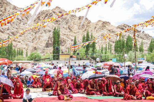Monks in their traditional red robes can be seen sitting on the ground at the Buddhist festival in Ladakh in the Himalayas