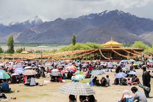 People wait under umbrellas in the harsh sun at the Buddhist temple in Ladakh in the Himalayas.
