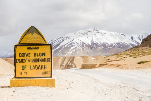 A road sign on the Manali to Leh Highway encourages drivers to drive slowly in the Himalayas.