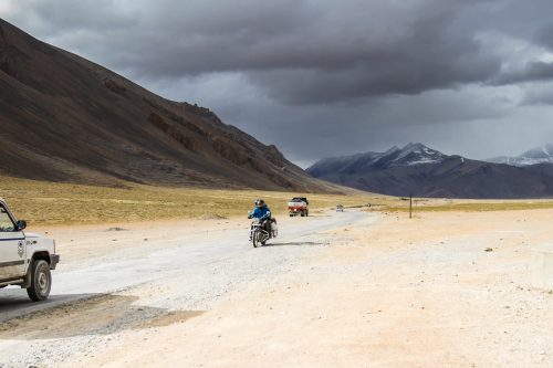 Trucks and motorcycles trail one another on the Manali to Leh Highway.