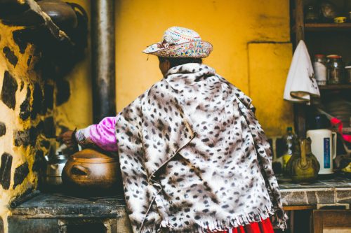 The back of Senora Julia, dressed in vibrant patterns, as she prepares soup