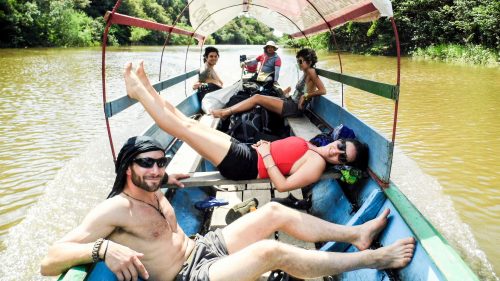 Tourists recline in the sunshine as their boat moves through the river in the Amazon jungle.