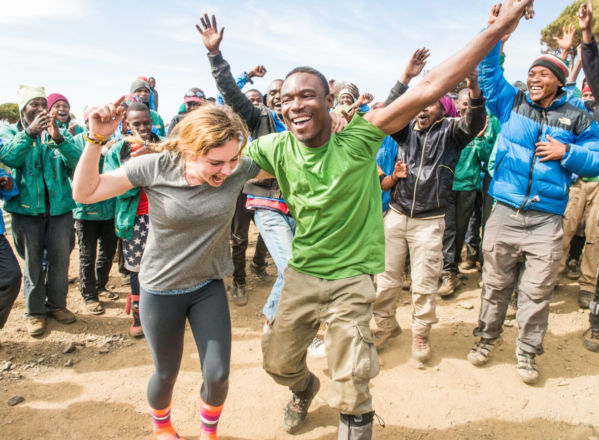 A tourist in Tanzania is jubilant and dances around with the crew from her hike.