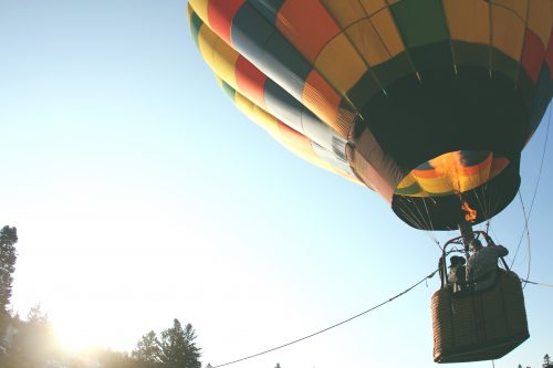 A hot air balloon takes off in the sunlight