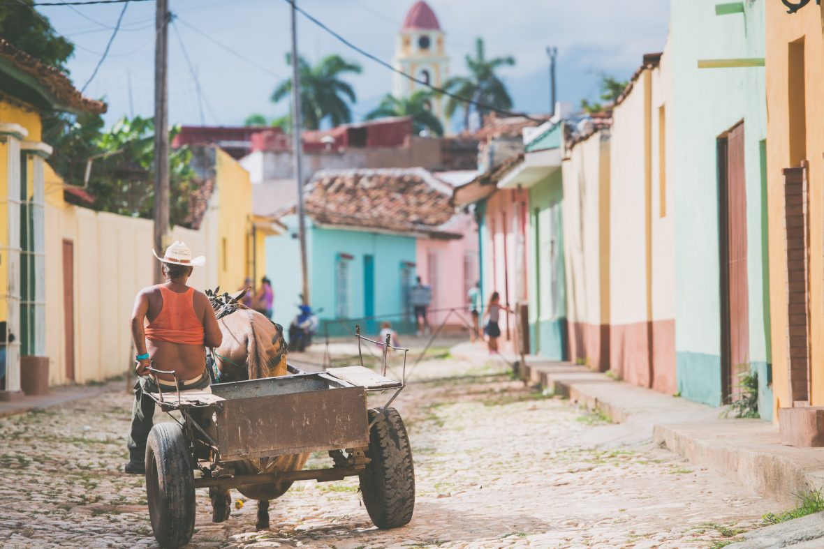 A man rides his horse and cart up one of the typically colorful streets of Trinidad, Cuba.