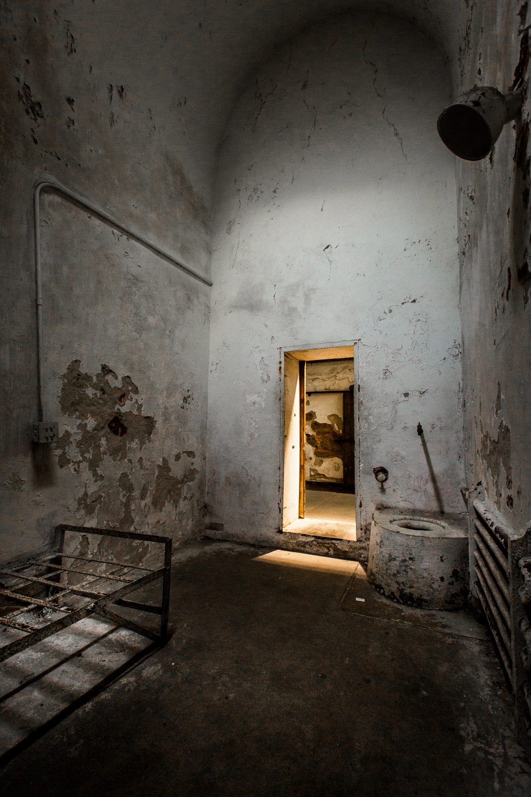 A rusty bed frame and cast iron toilet in cell block one.