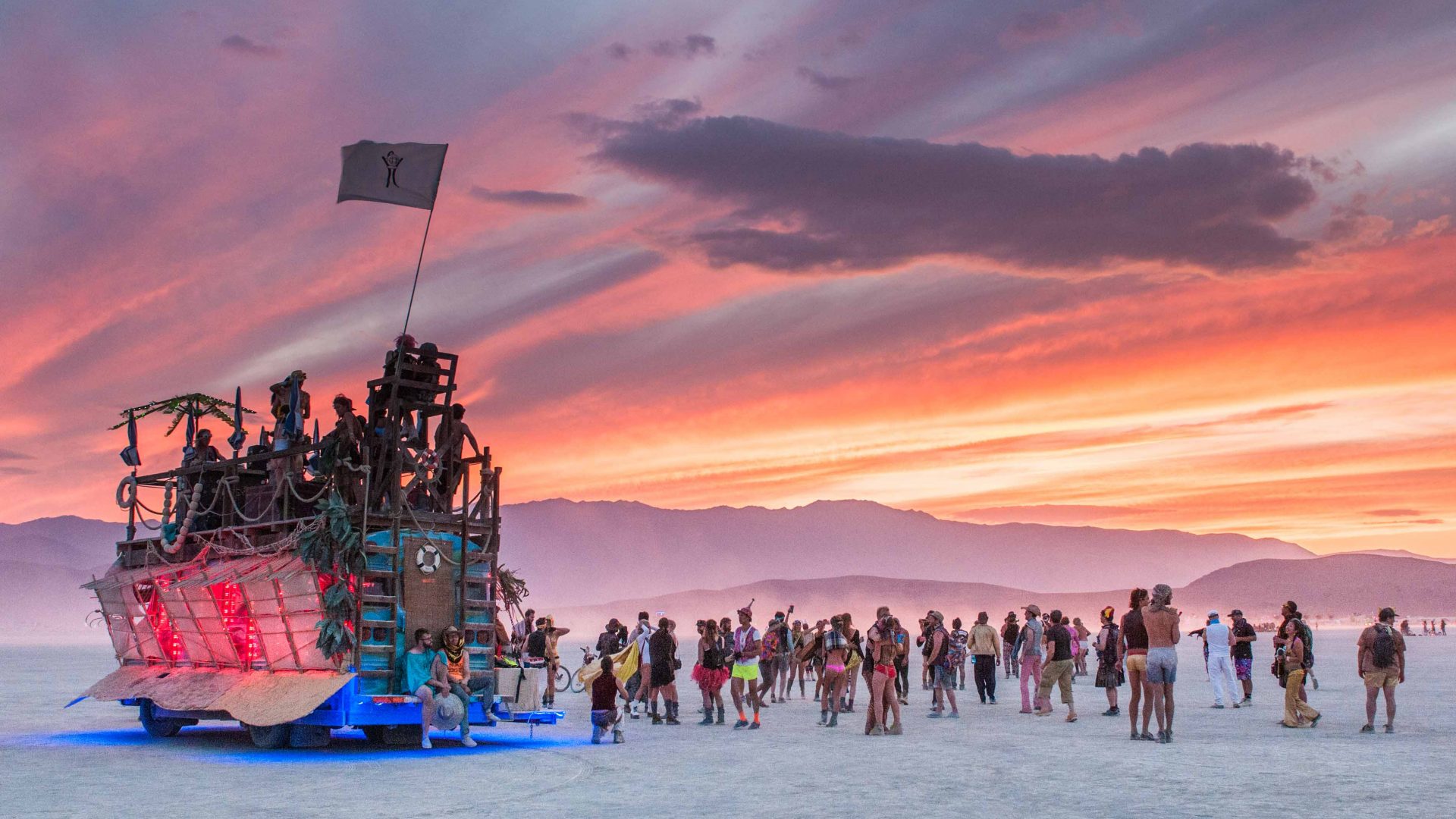 As the sun sets over Burning Man, an art car stands tall over attendees down below.