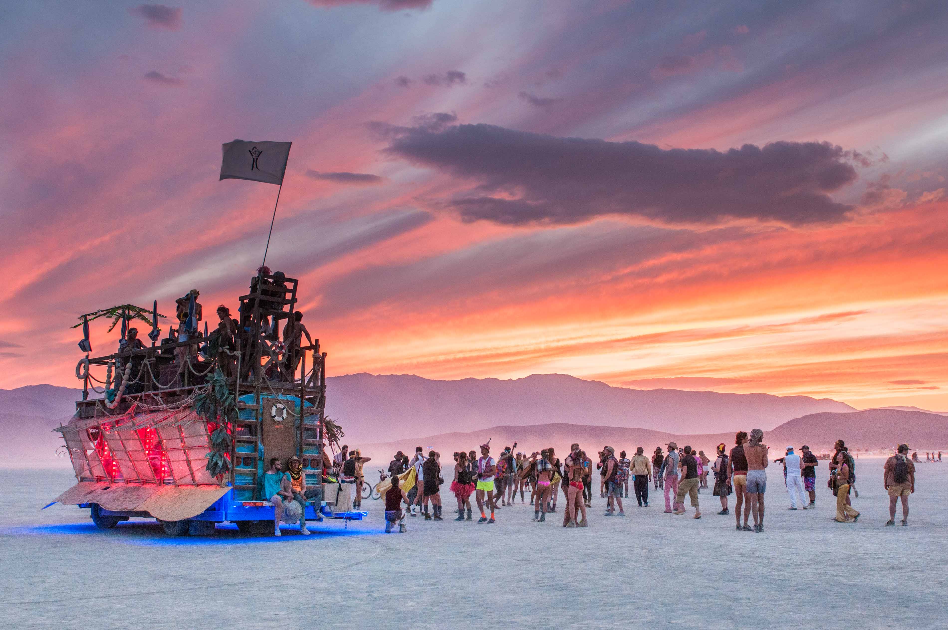 As the sun sets over Burning Man, an art car stands tall over attendees dow...