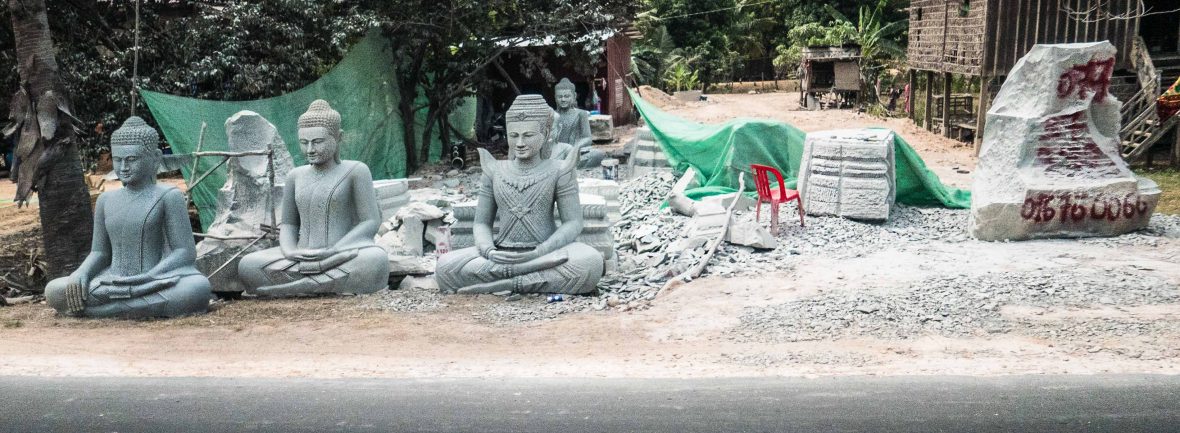 Plastic chairs of Southeast Asia: A sculptor's plastic chair as he works on a series of large, stone Buddhas.