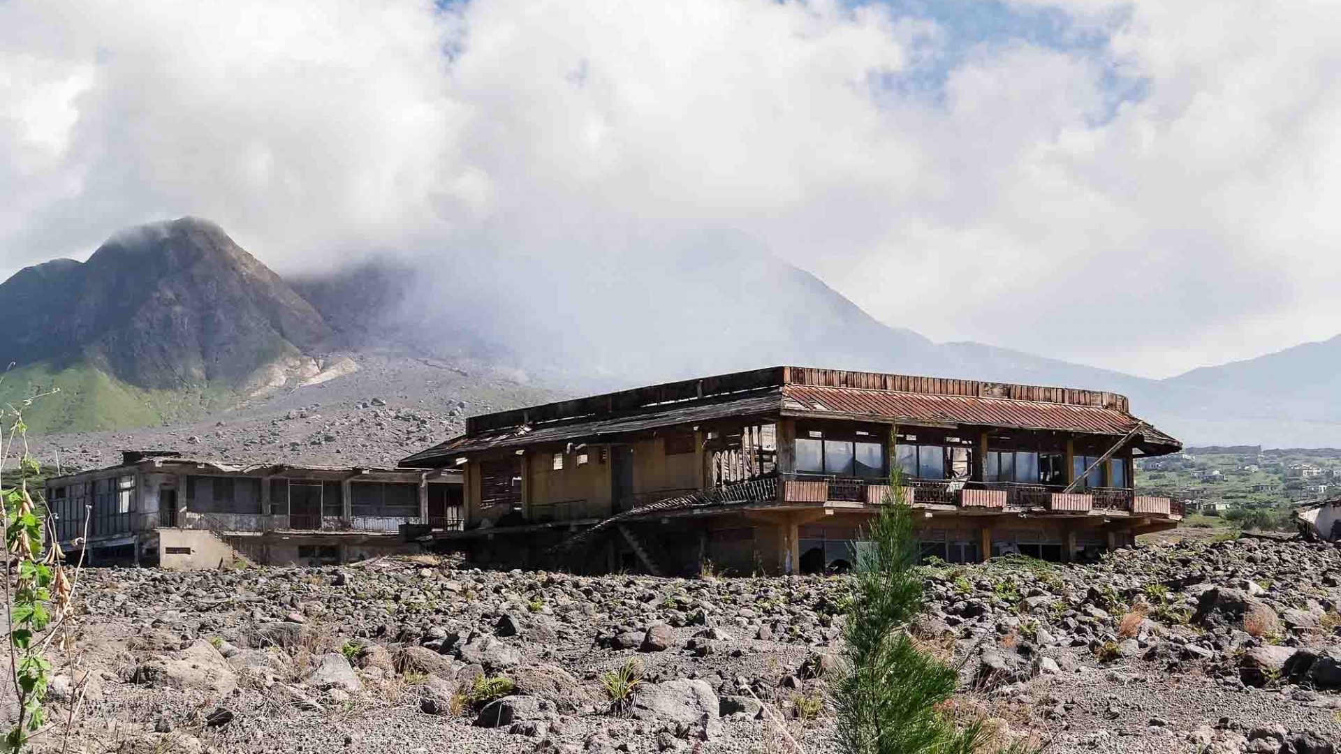 Montserrat's Soufrière Hills volcano stands behind an abandoned house in what has become known as a modern-day Pompeii.
