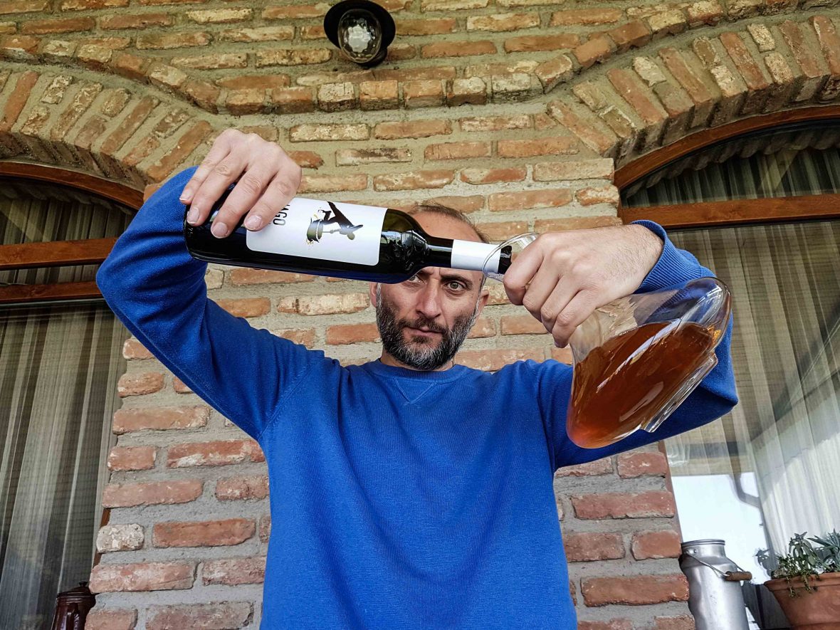 Iago of Iago's Winery pours a bottle of biodynamic wine into a carafe.