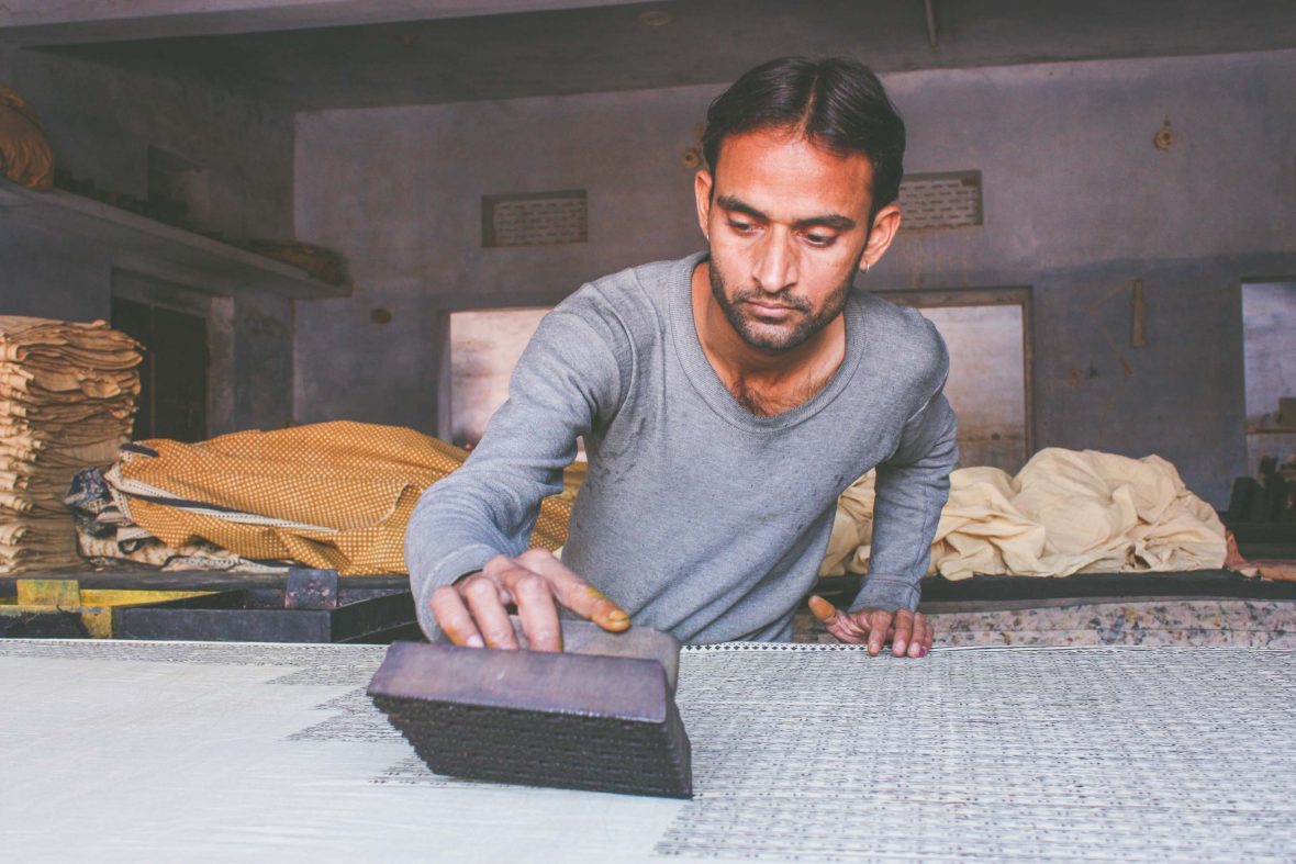 A printer at one of the workshops in Bagru carefully applies his block to the textile he is working on.