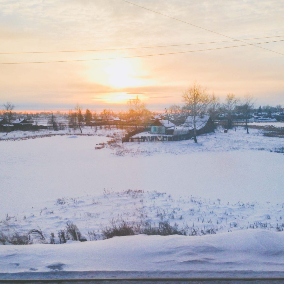 The warm glow of the sun as it sets over a frosty winter day in Russia.