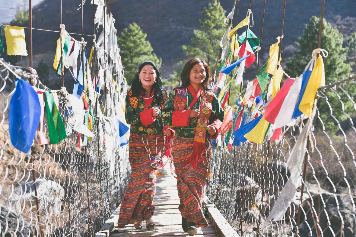 Two women run across the foot bridge at Tachogang Lhakhang – meaning “Temple of the Excellent Horse”.