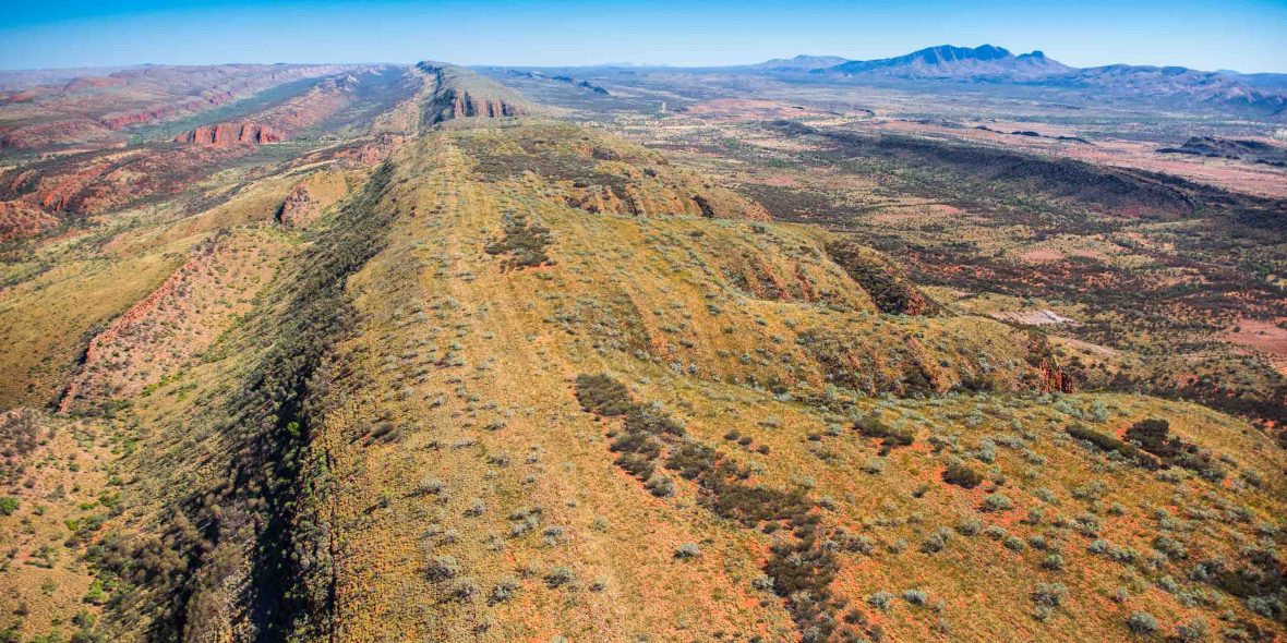 An aerial view over the West MacDonnell Ranges, with Mount Sonder in the background.