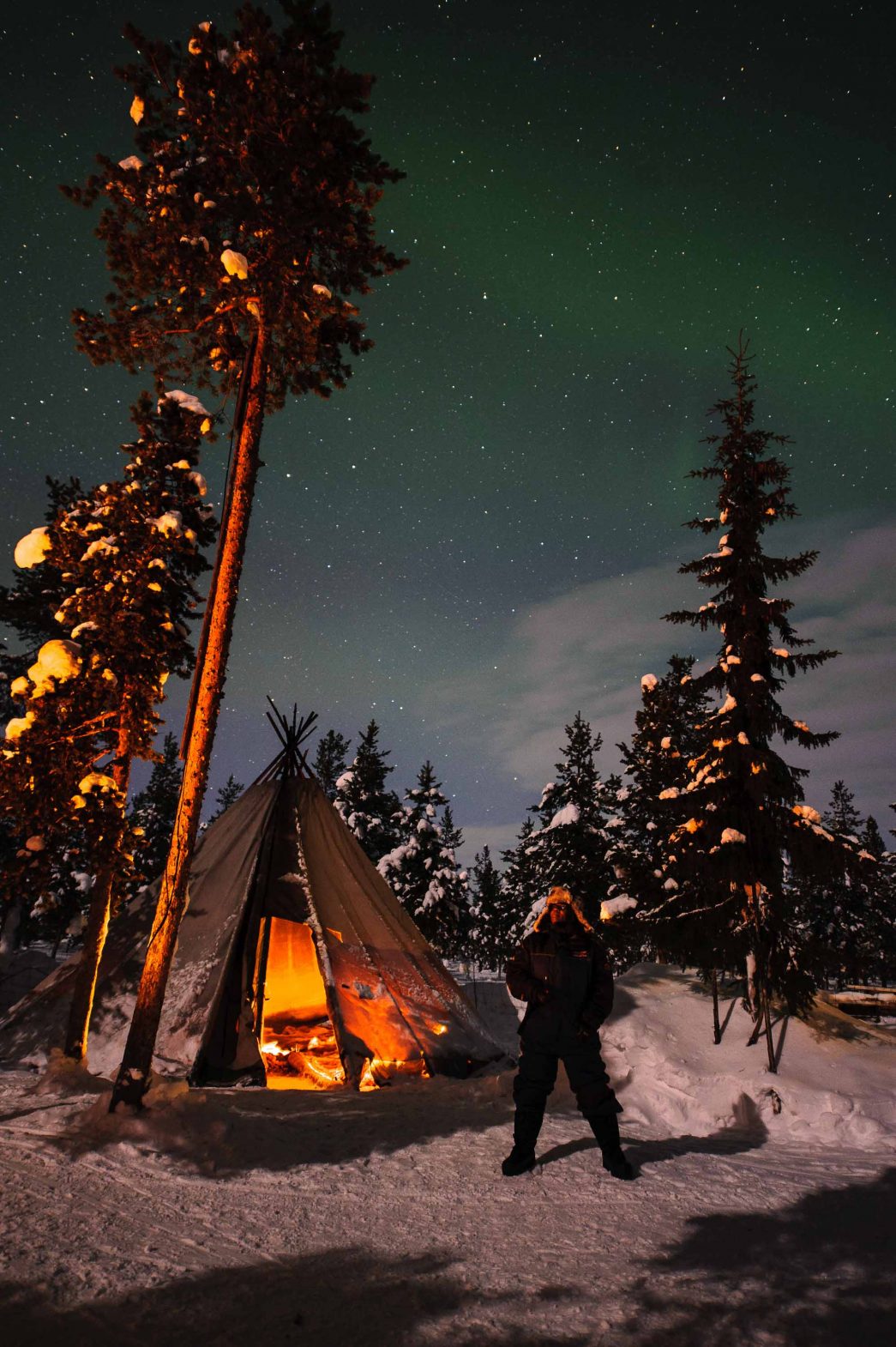 Lola looks up at the northern lights above tents at the reindeer lodge in Sweden.