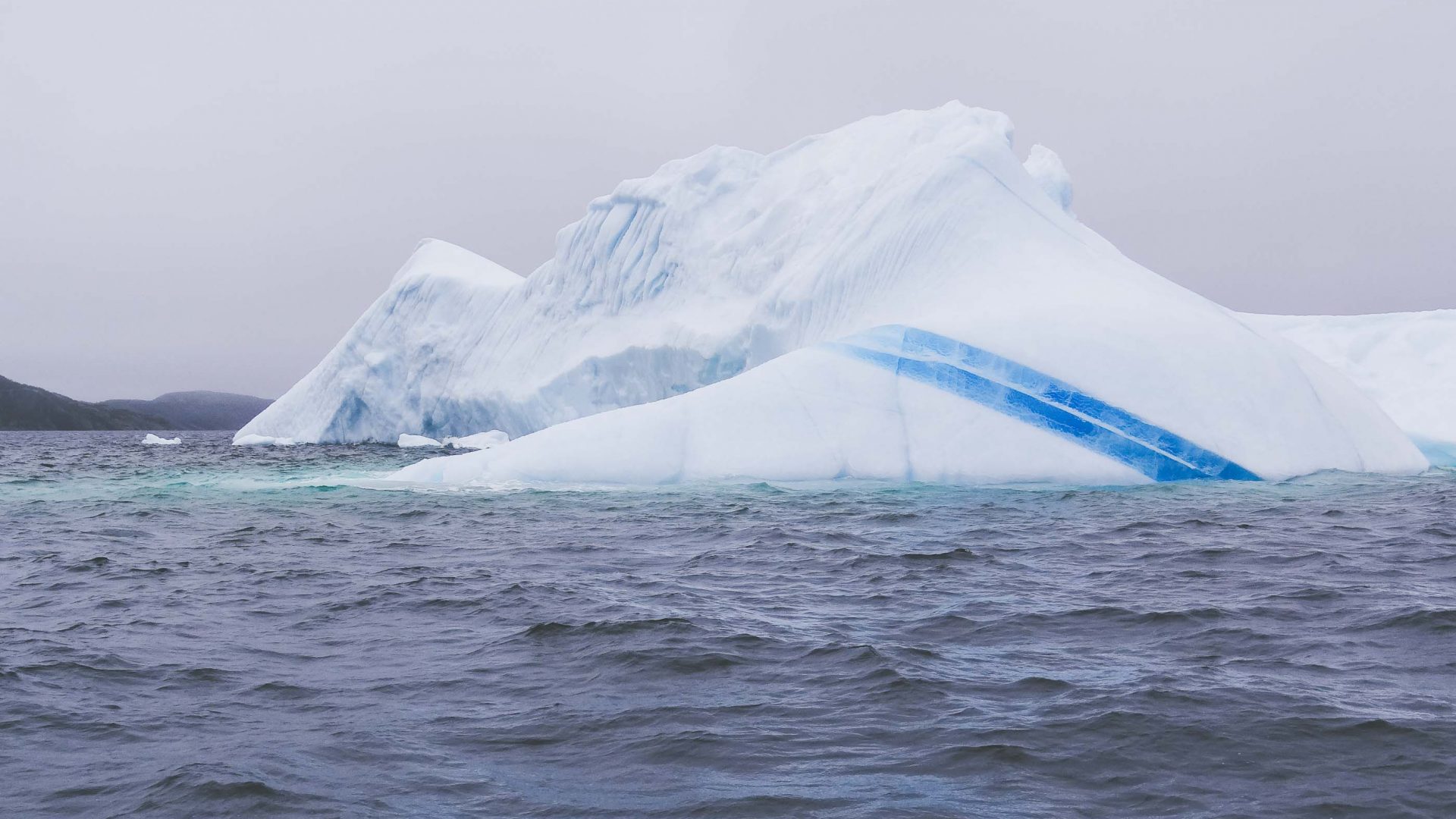 A beached iceberg in Newfoundland has rich blue veins running through it.