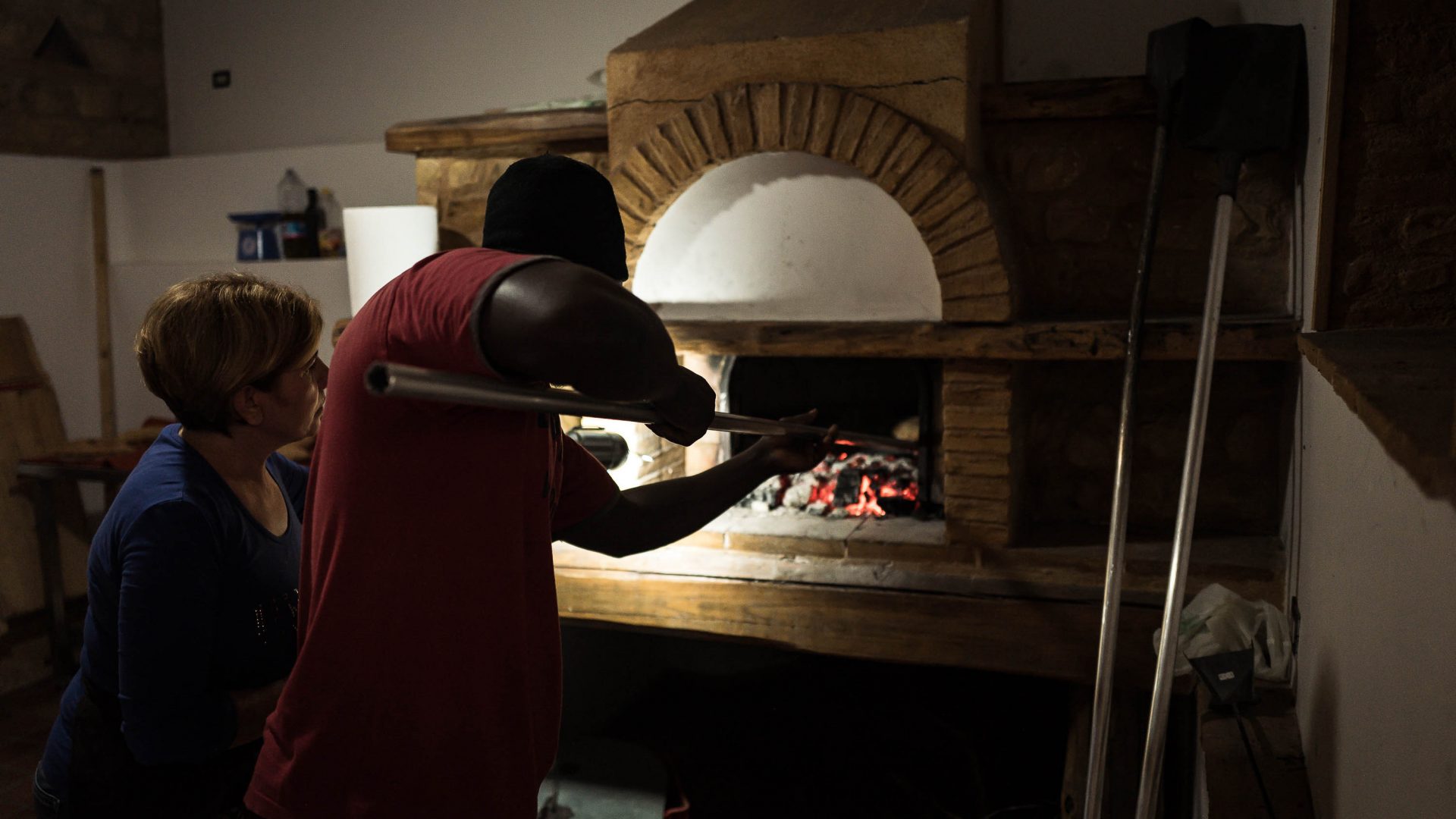 Kolli from Gambia is being taught by Teresa from Camini how to make bread in the oven the traditional way.