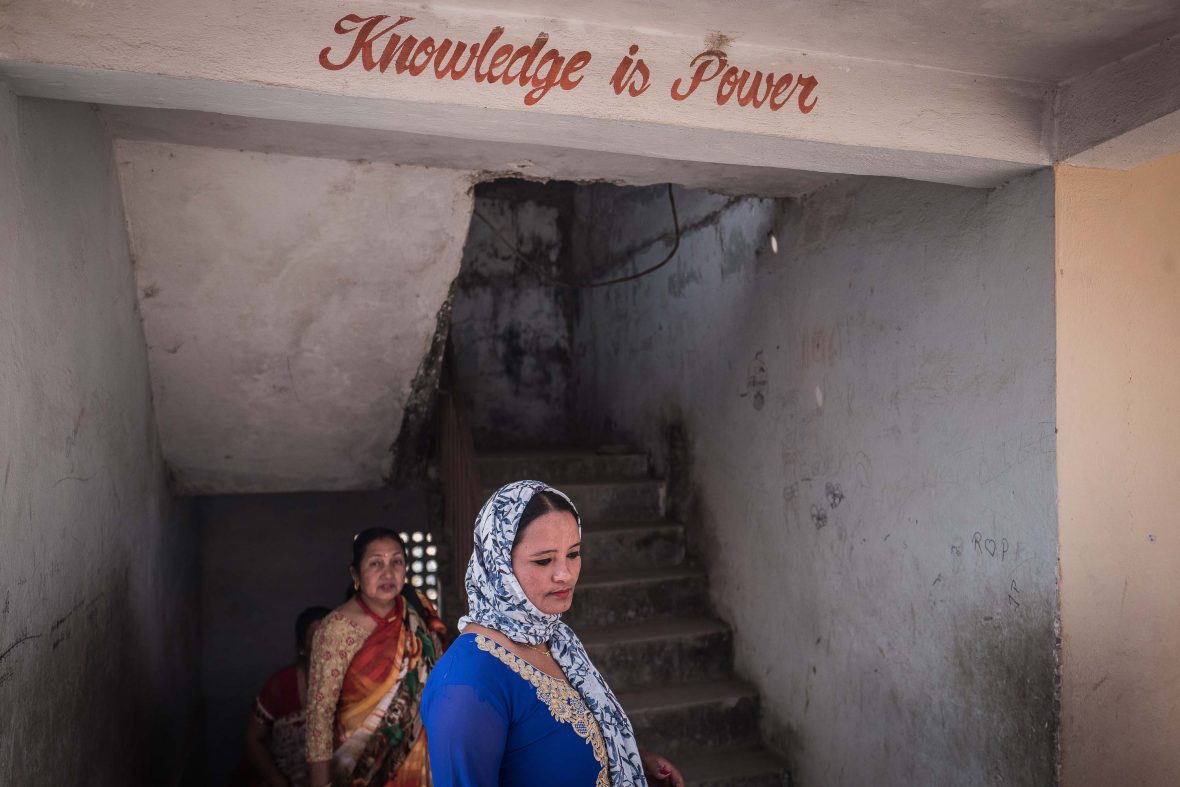 Women gather at a school hall with a sign above them that aptly reads 'knowledge is power'.