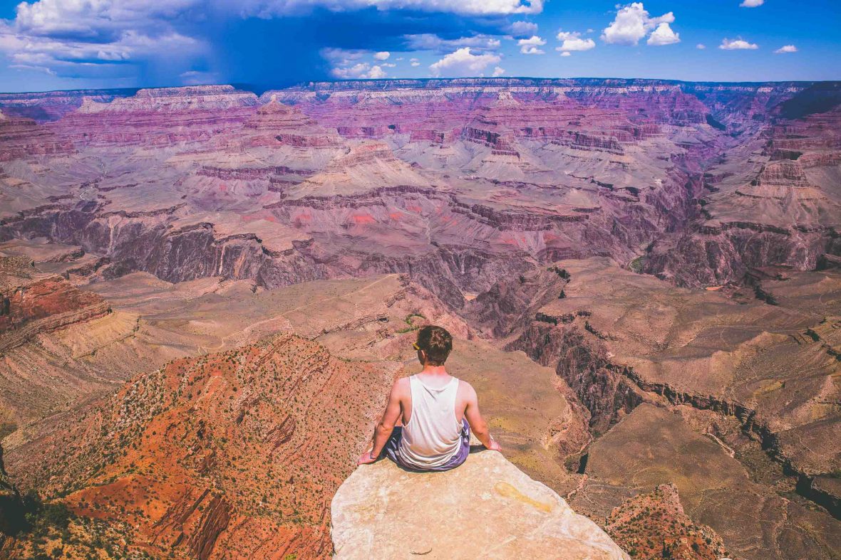A man sits on the edge of a precipice at the Grand Canyon in the USA.