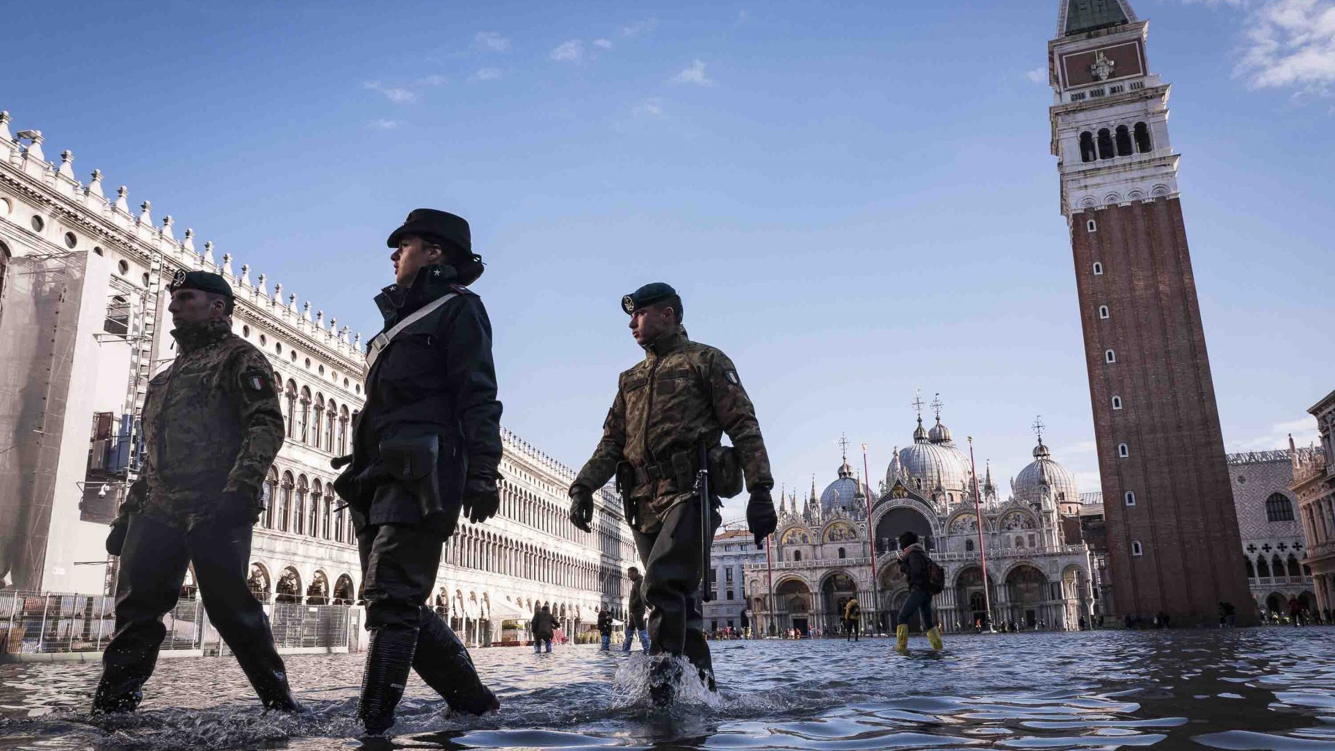 Police and army officials walking through a flooded Piazza San Marco.