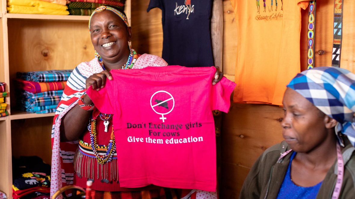 Hellen holds up a t-shirt with the motto 'Don't exchange girls for cows, give them an education' in the Maasai Tepesua village.