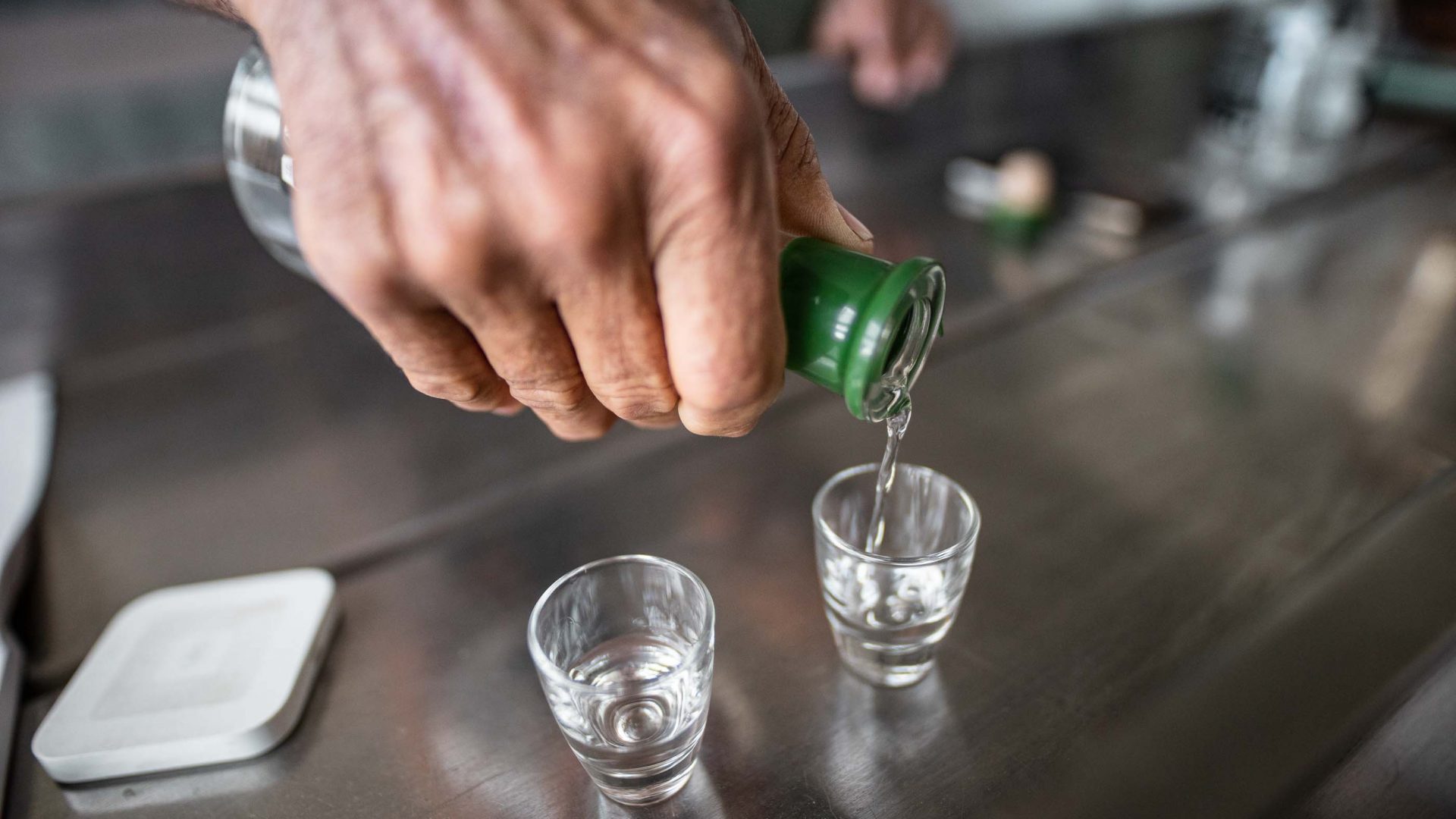 A hand pours a shot of alcohol