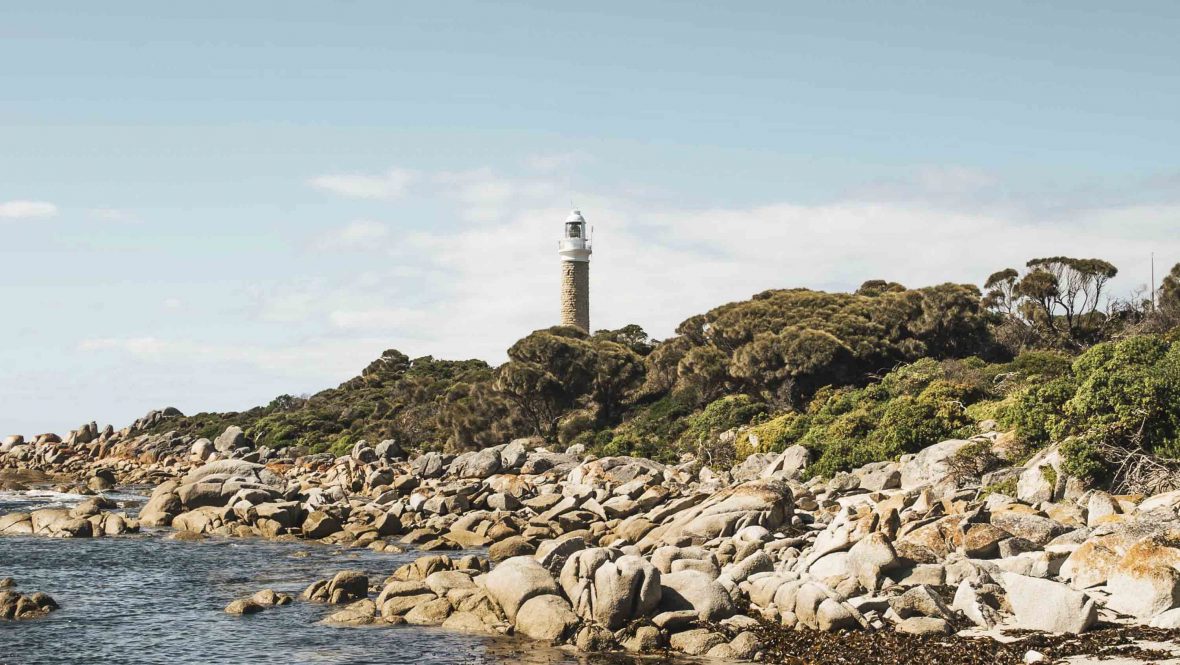 The larapuna lighthouse stands sentinel against the striking Bay of Fires, with its white-sand beaches and orange-lichen granite boulders.