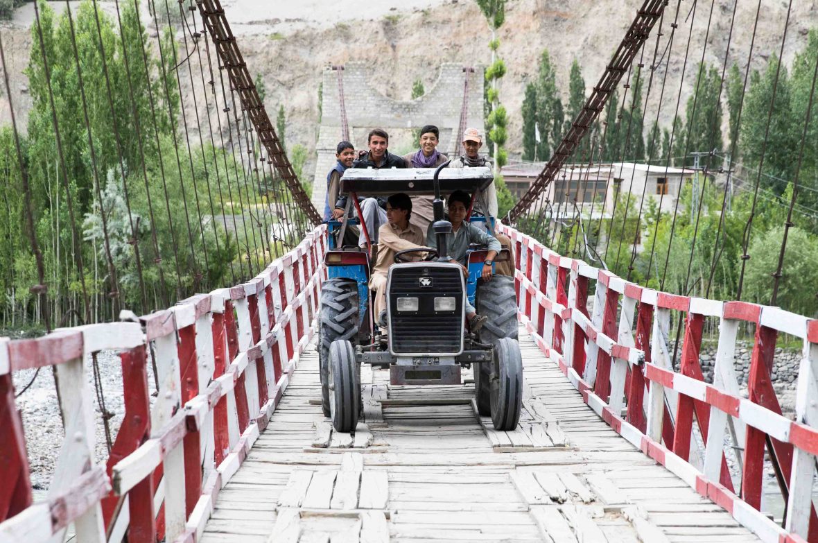 School children heading home by tractor on a one lane bridge.