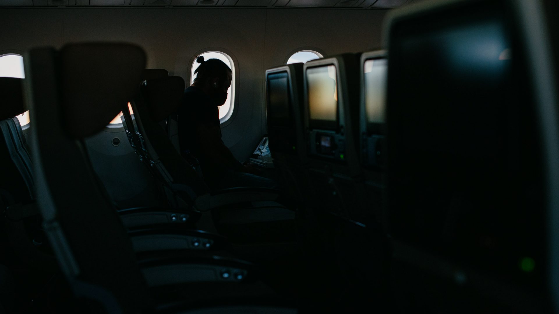 A passenger in the dark airplane cabin.