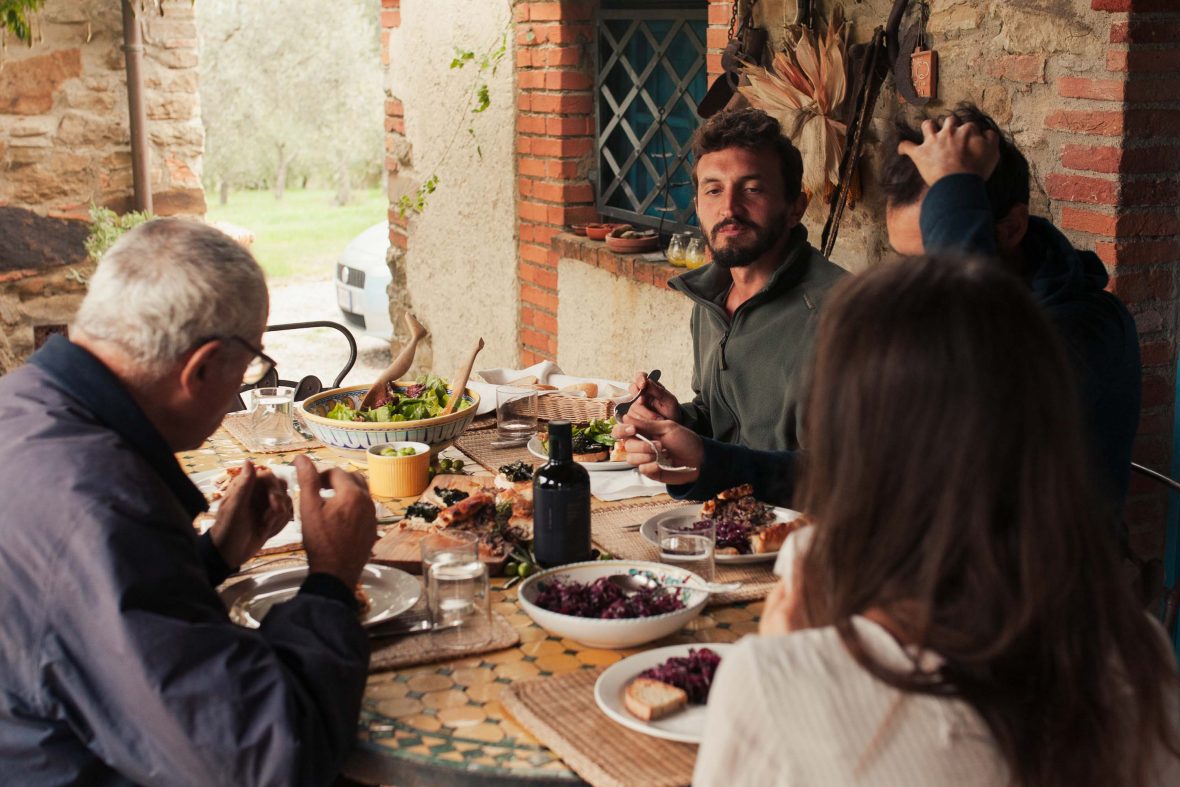 Olive pickers gather round a table of food at the farmhouse