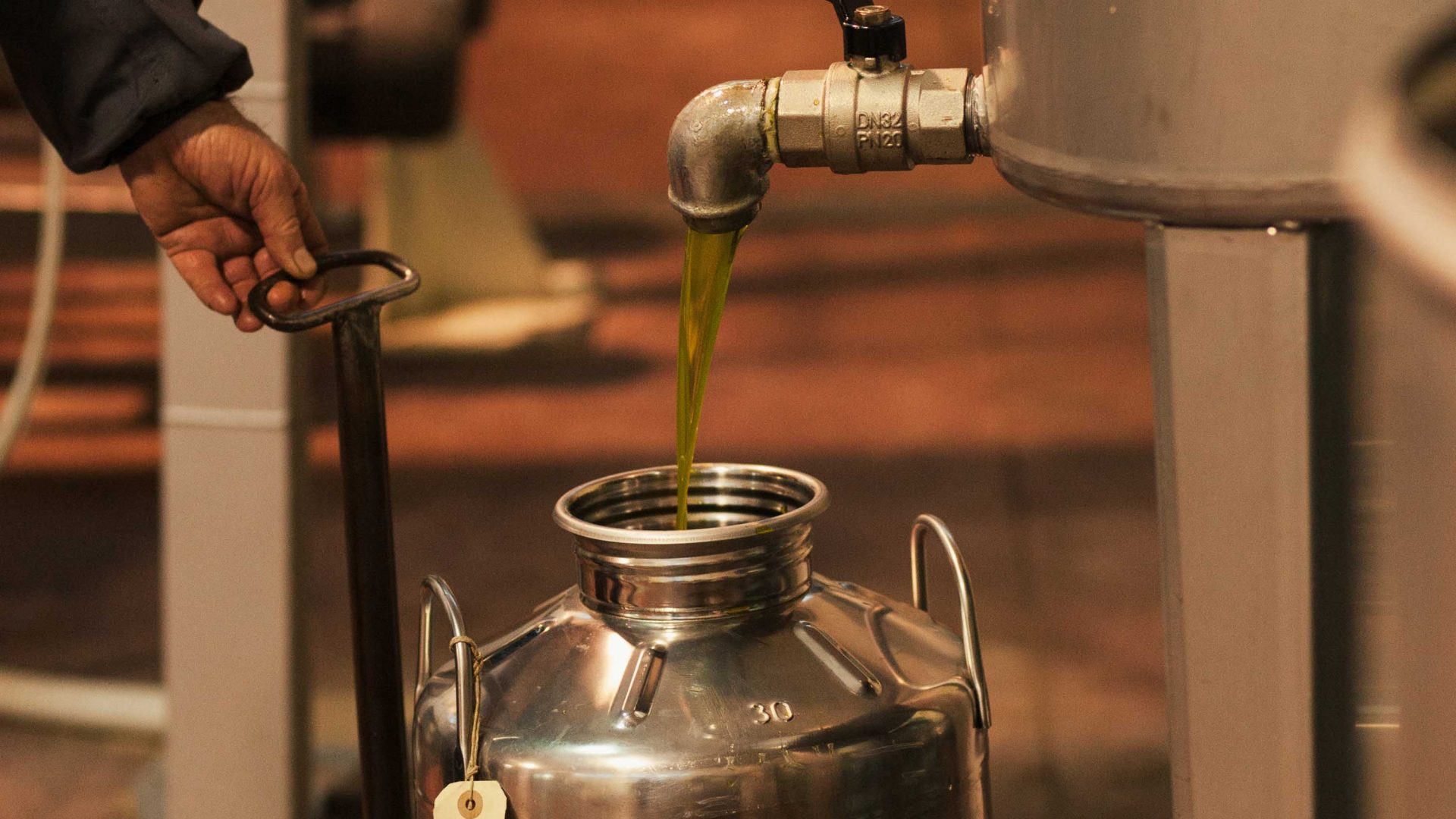 Olive can be seen pouring from a vat into a jar.