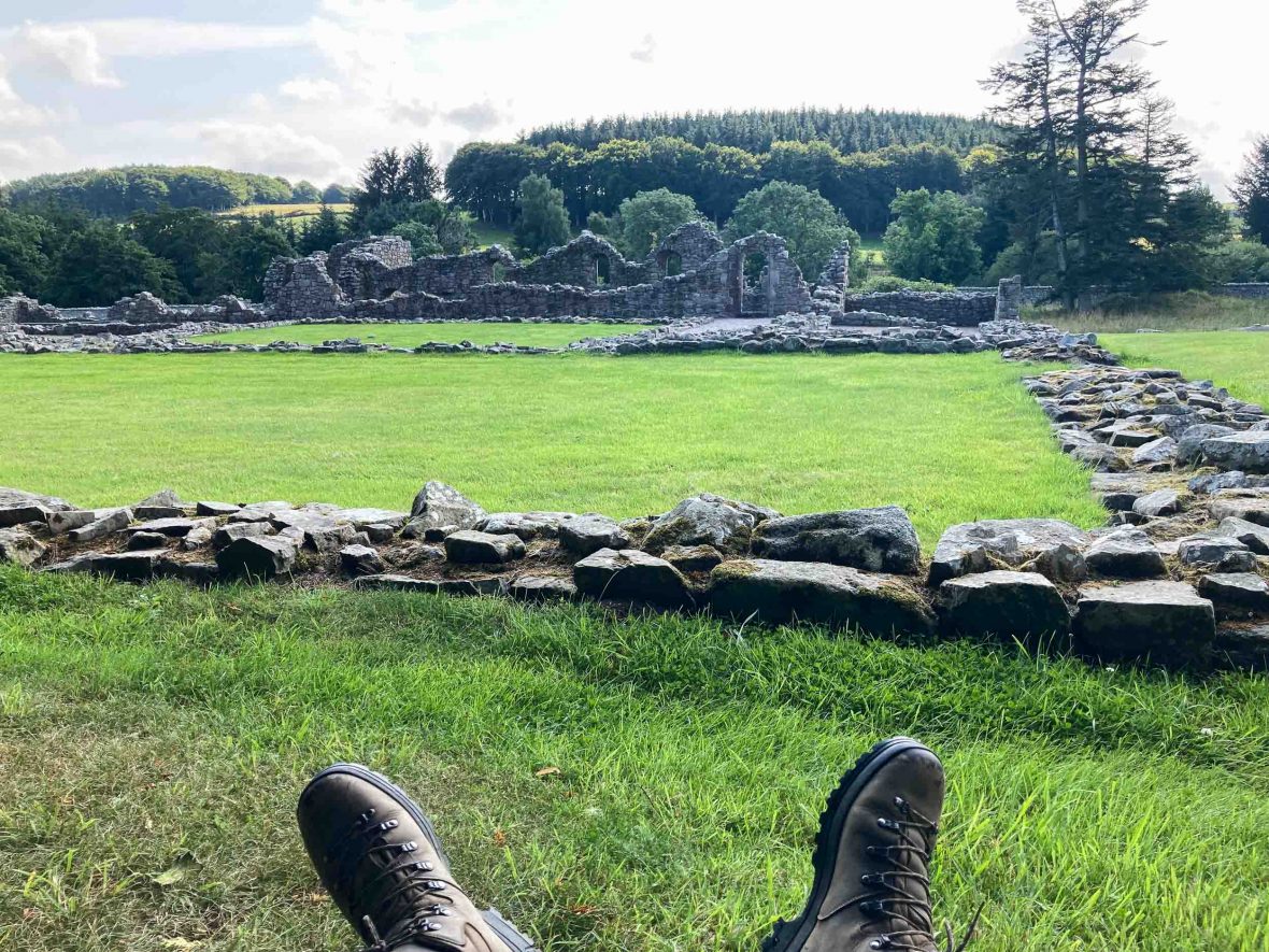 Shoes seen resting by green fields with stones in it.