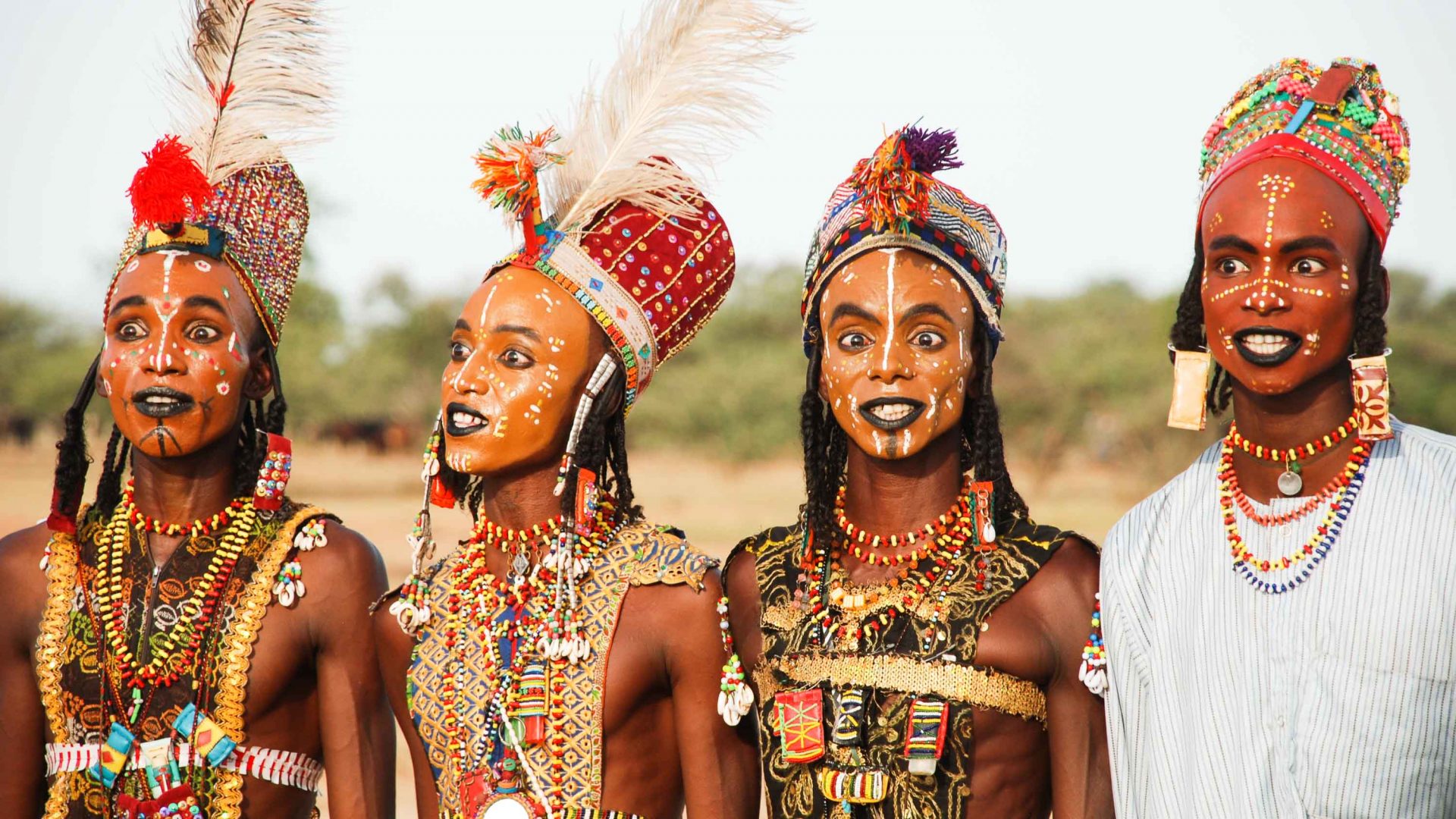 Three men adorned in necklaces and headdresses.