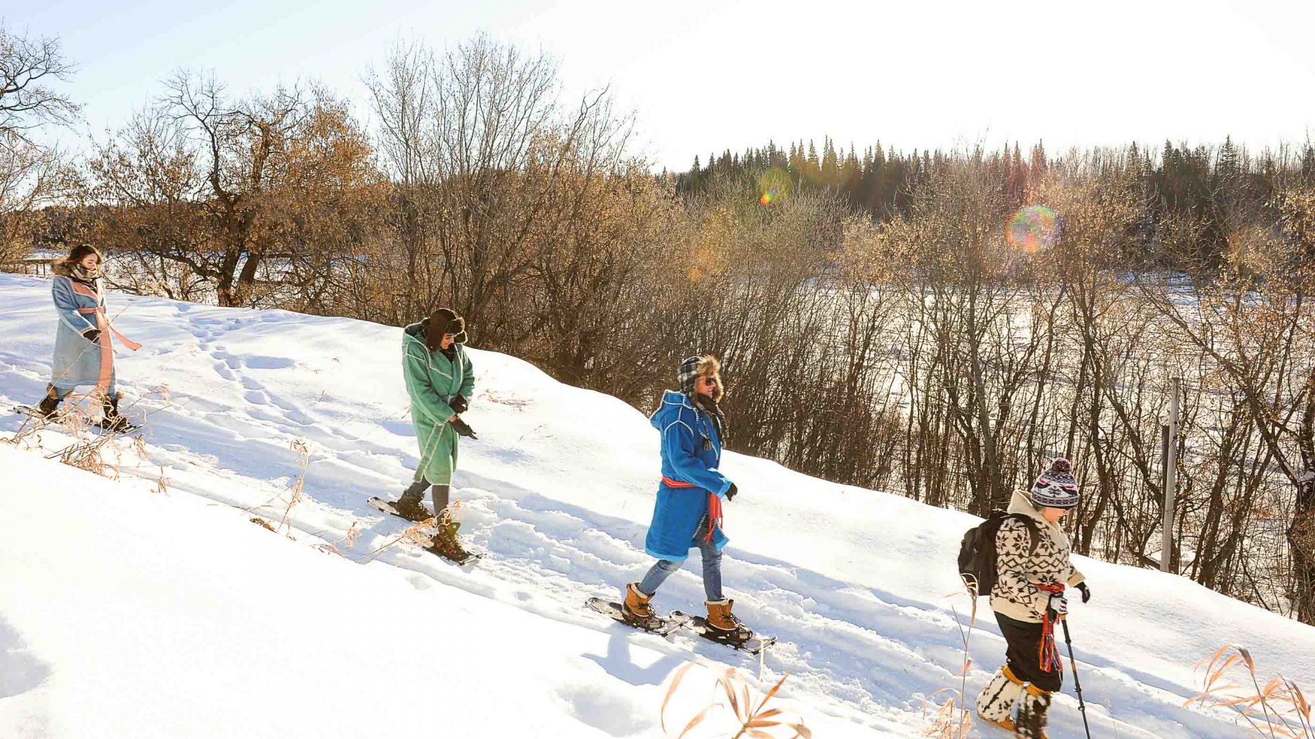 Guests walk in snow shoes down a trail.