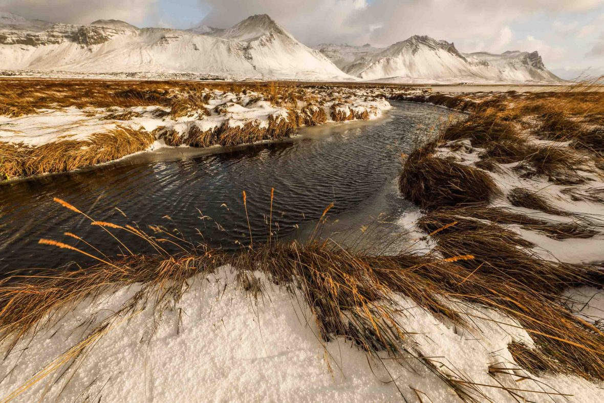 Channels of water break through ice, creating a brown and white landscape.