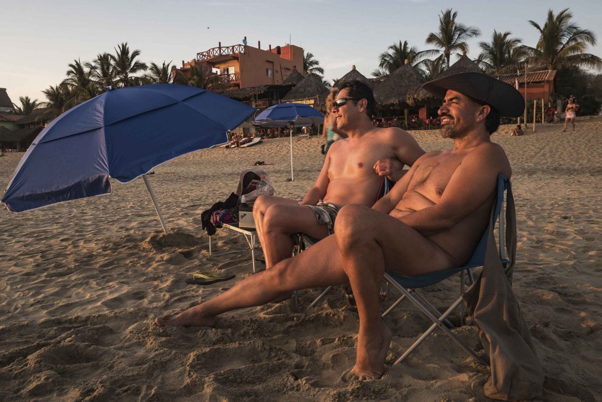 Two men sit on beach chairs in the soft light of the sun.