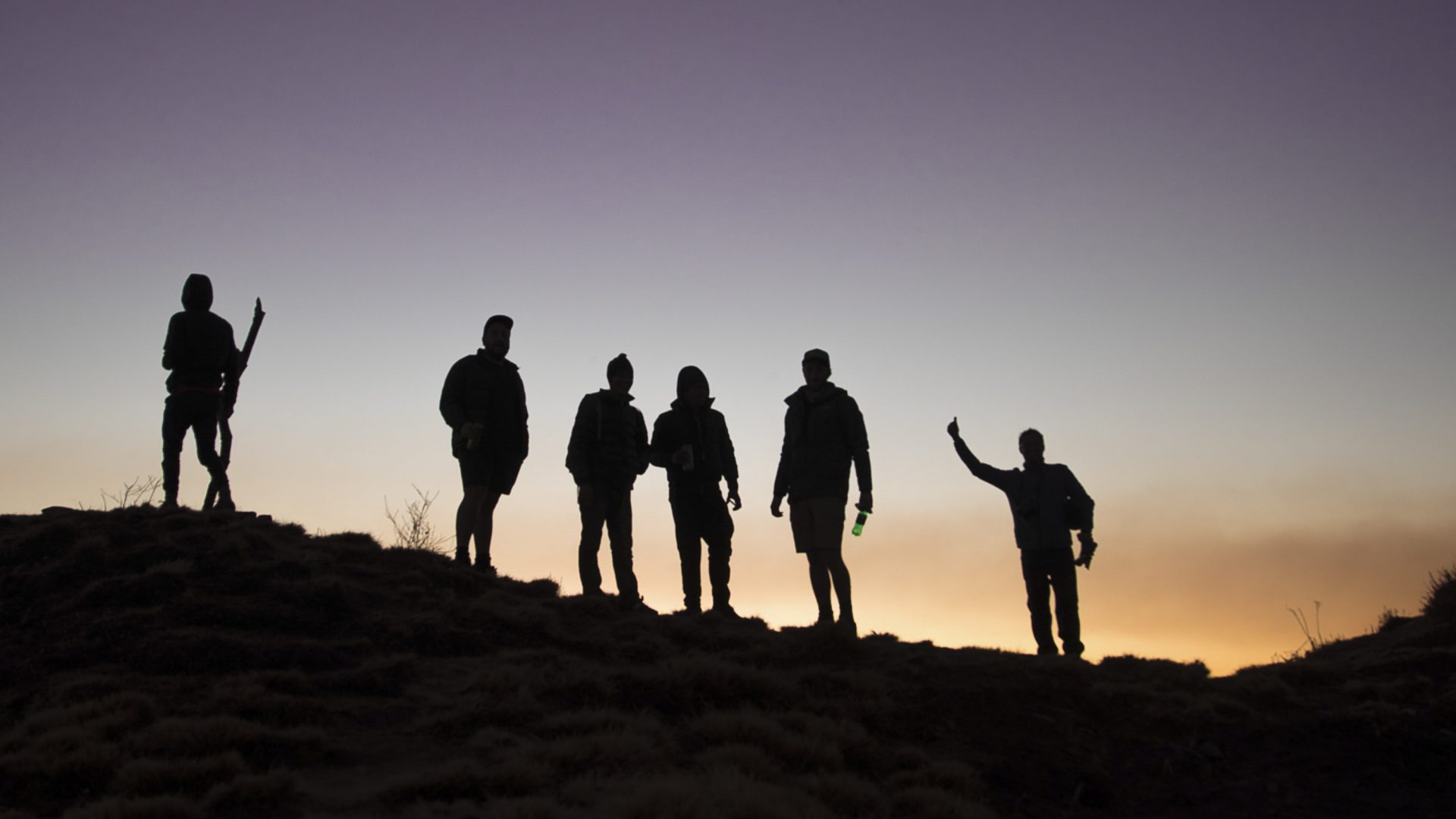 Silhouettes of six hikers on a mountain.