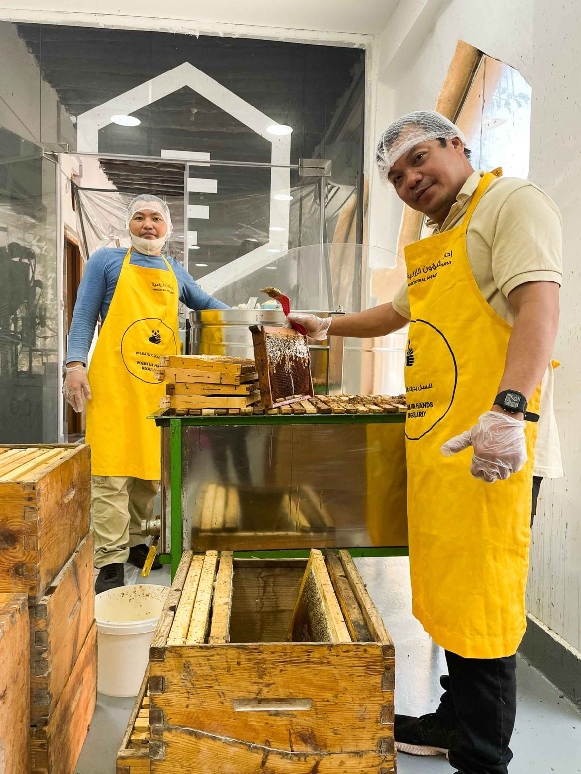 Two men in yellow aprons work to extract honey.