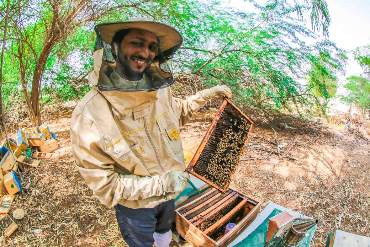 Khalid shows off his bees while smiling to camera.