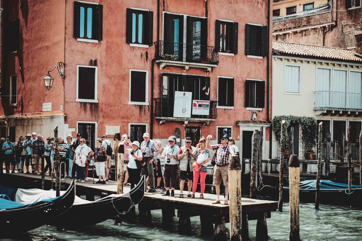 Tourists line iup along the water with their cameras, ready to take photos in Venice.