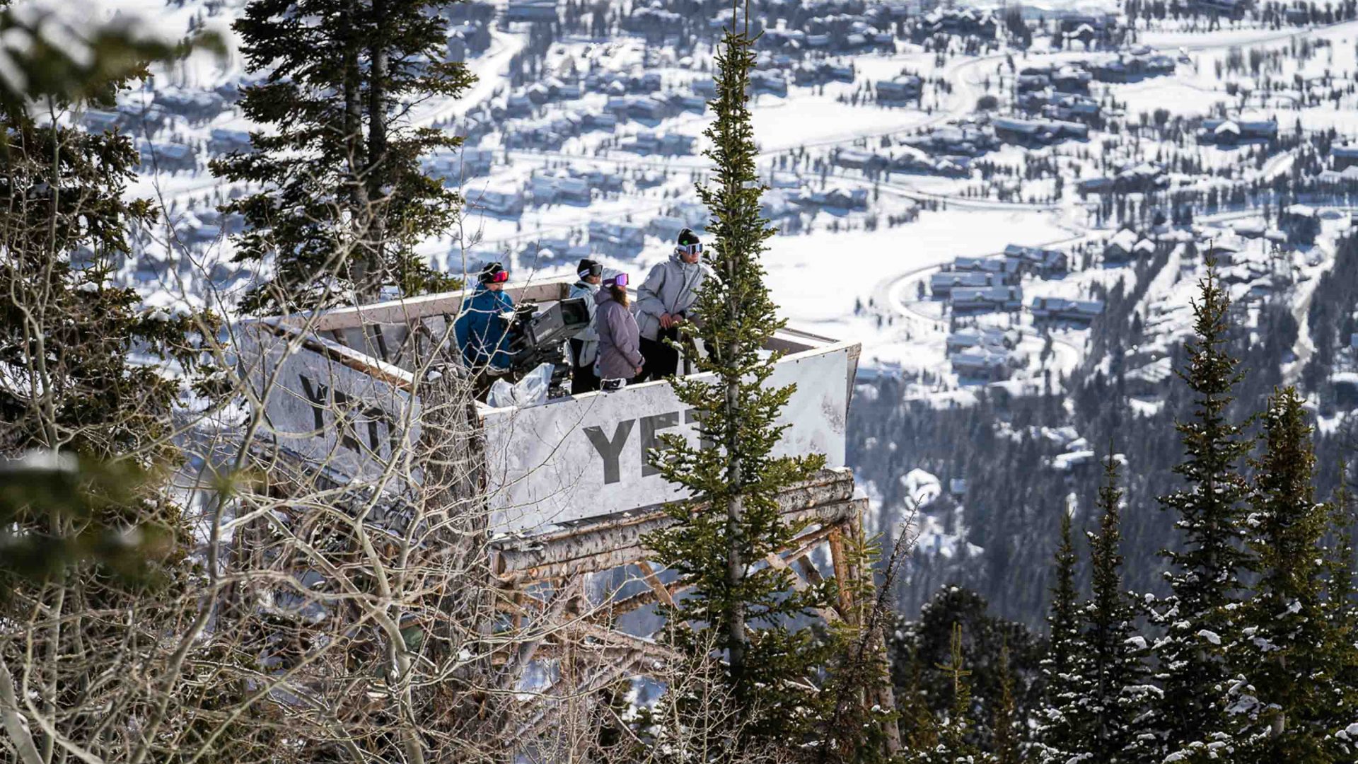 A lookout where several skiers and snowboarders stand looking out.